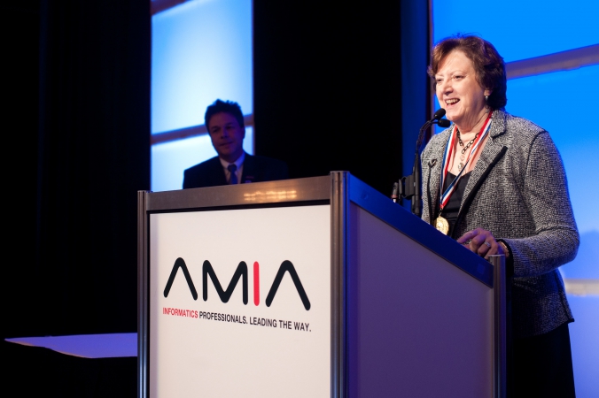 photo of award recipient addresses audience from podium, amia annual symposium