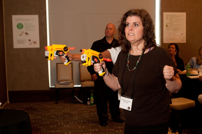 woman shoots nerf gun, break out session,  corporate event photography, team building games, merck product launch, rosemont convention center